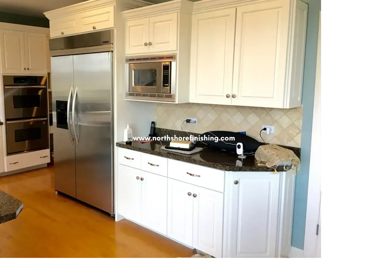 White kitchen cabinets with stainless steel appliances and granite countertops.