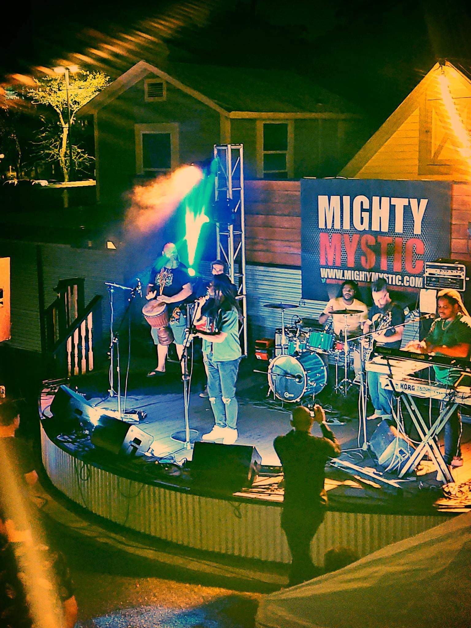 A crowd watching a live band on the outdoor stage at Depot Village in downtown Gainesville at night