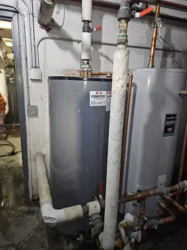 Gray water heaters with pipes and valves in a basement utility area