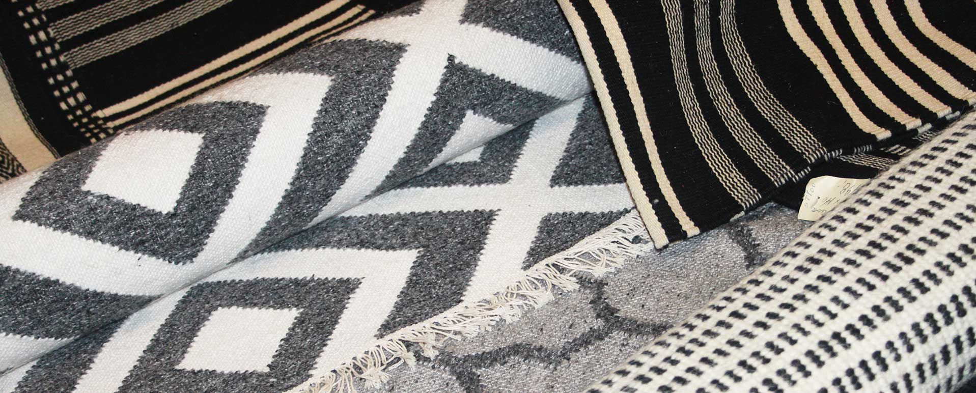 Et nærbillede af et sort og hvidt tæppe og puder på en seng.