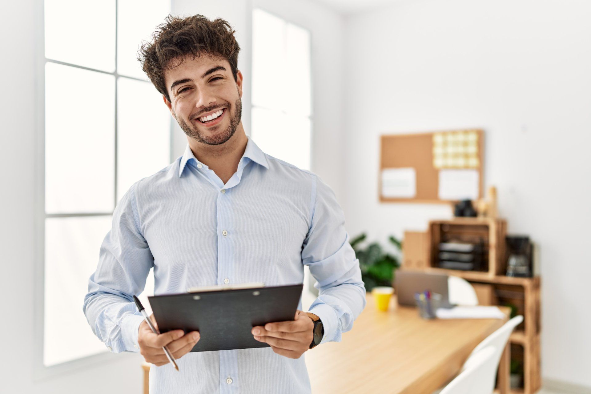 a man in a blue shirt is holding a clipboard and smiling