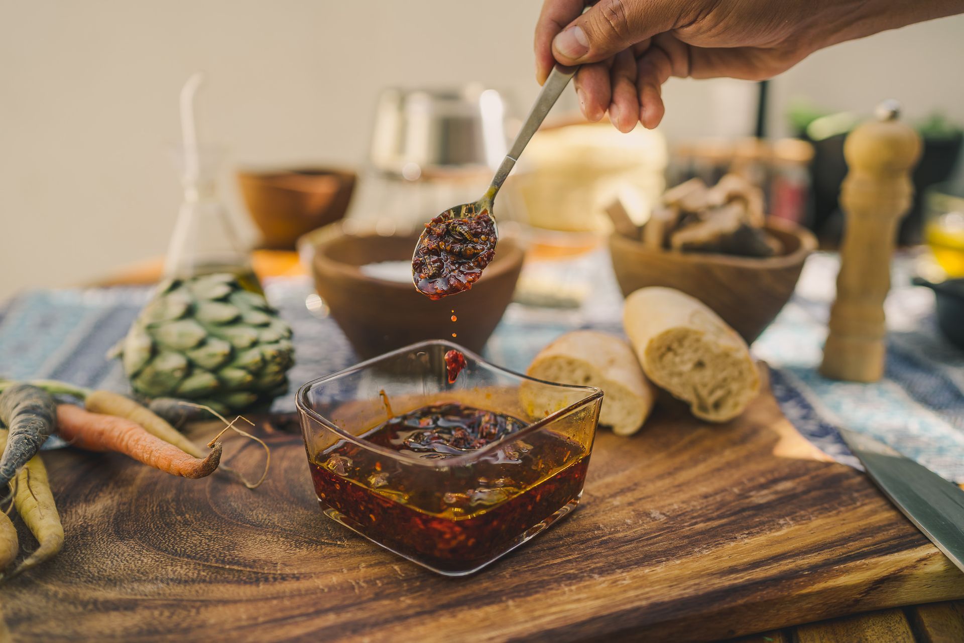 Salsa macha  sobre una mesa de madera con pan y aperitivos.