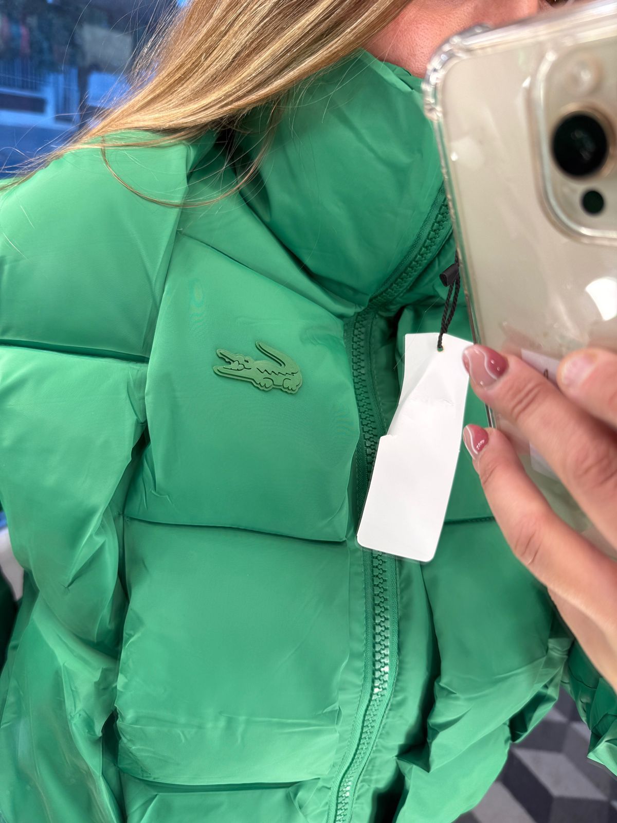 Mujer con chaqueta verde tomándose una selfie en el interior.