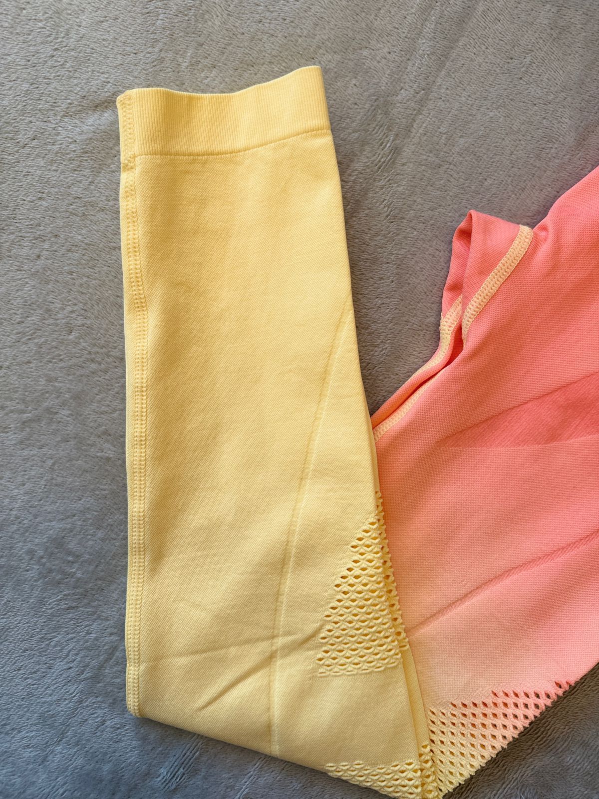 Leggings de entrenamiento con efecto ombré en color melocotón y amarillo sobre tela gris.