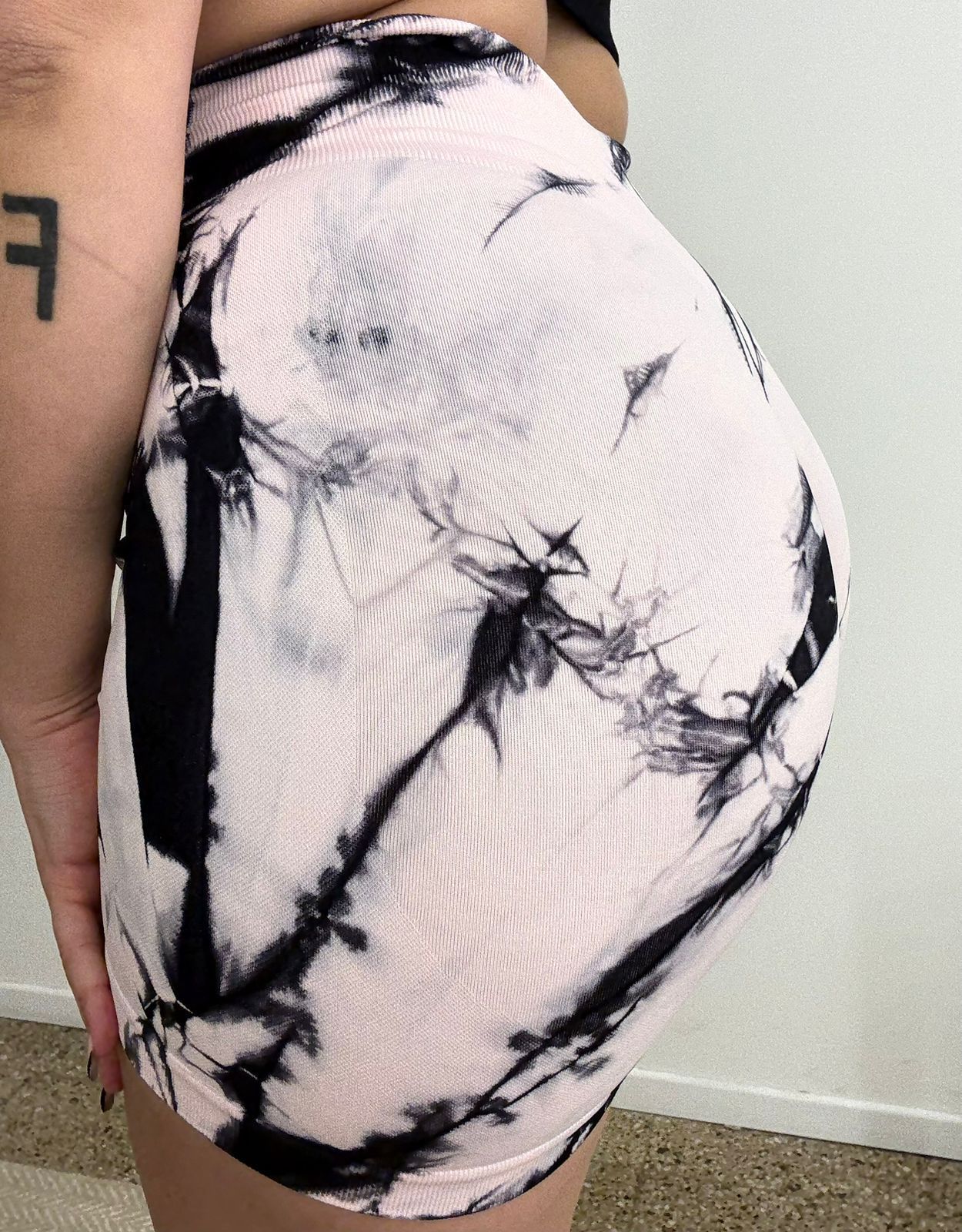 Mujer con pantalones cortos tie-dye de color rosa y negro, con las manos en las caderas.