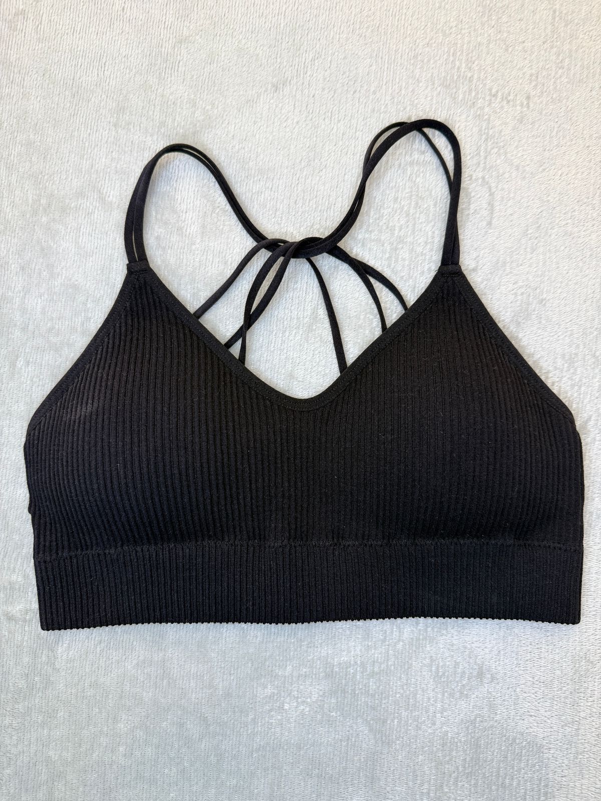 Mujer que lleva un sujetador deportivo negro con tirantes cruzados, vista posterior, arte del tatuaje en la espalda.