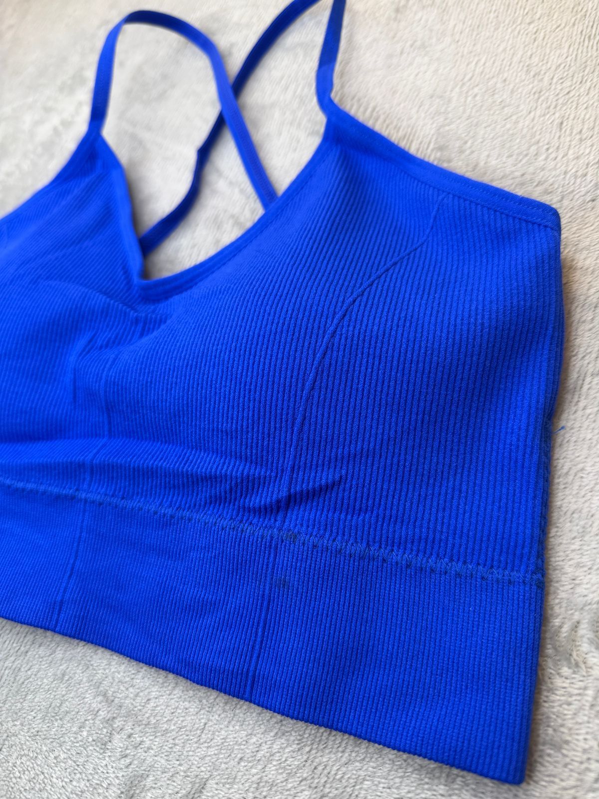 Sujetador deportivo de canalé azul con tirantes cruzados en la espalda.