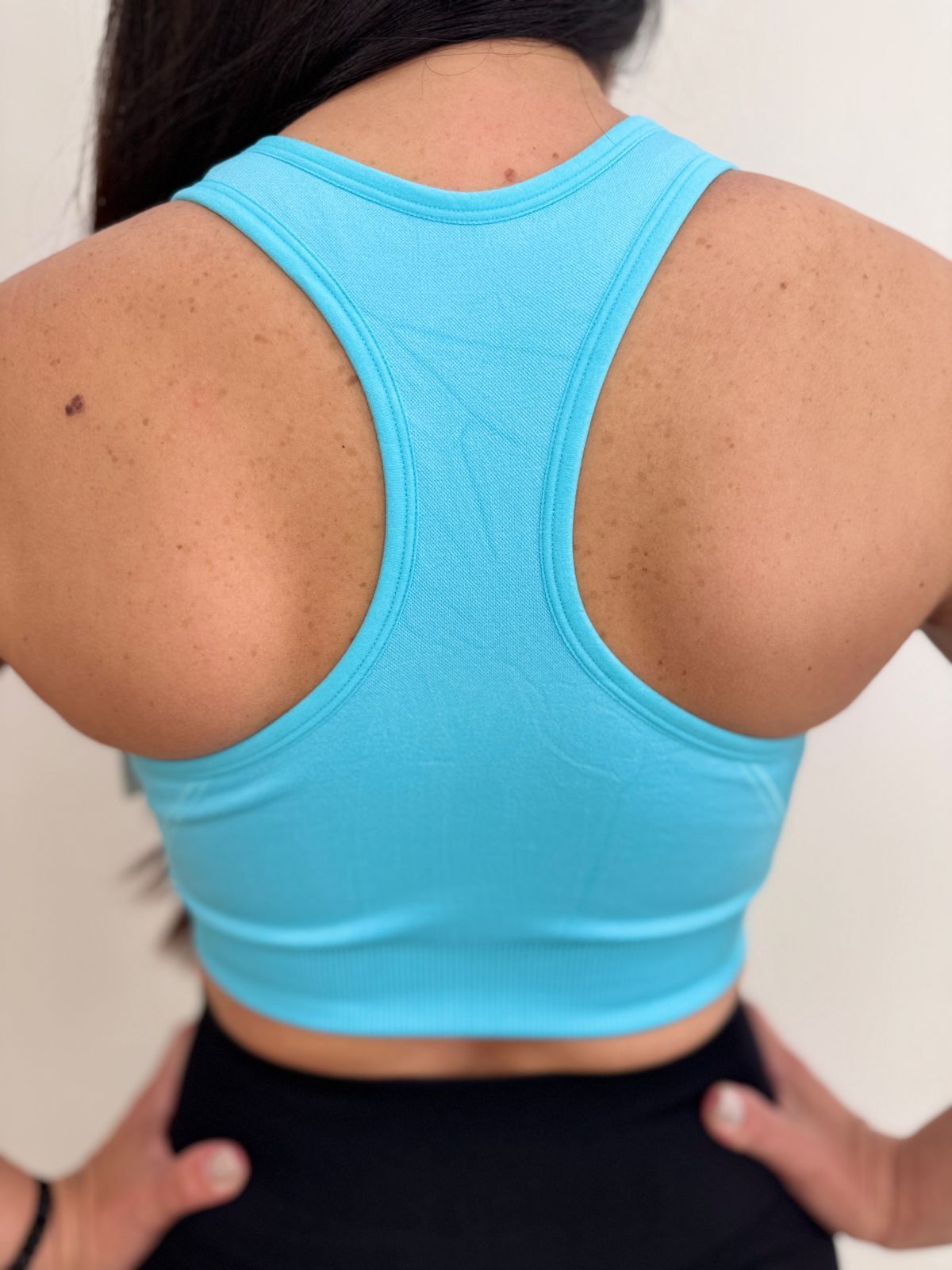 Mujer que lleva un sujetador deportivo azul claro con cremallera central.