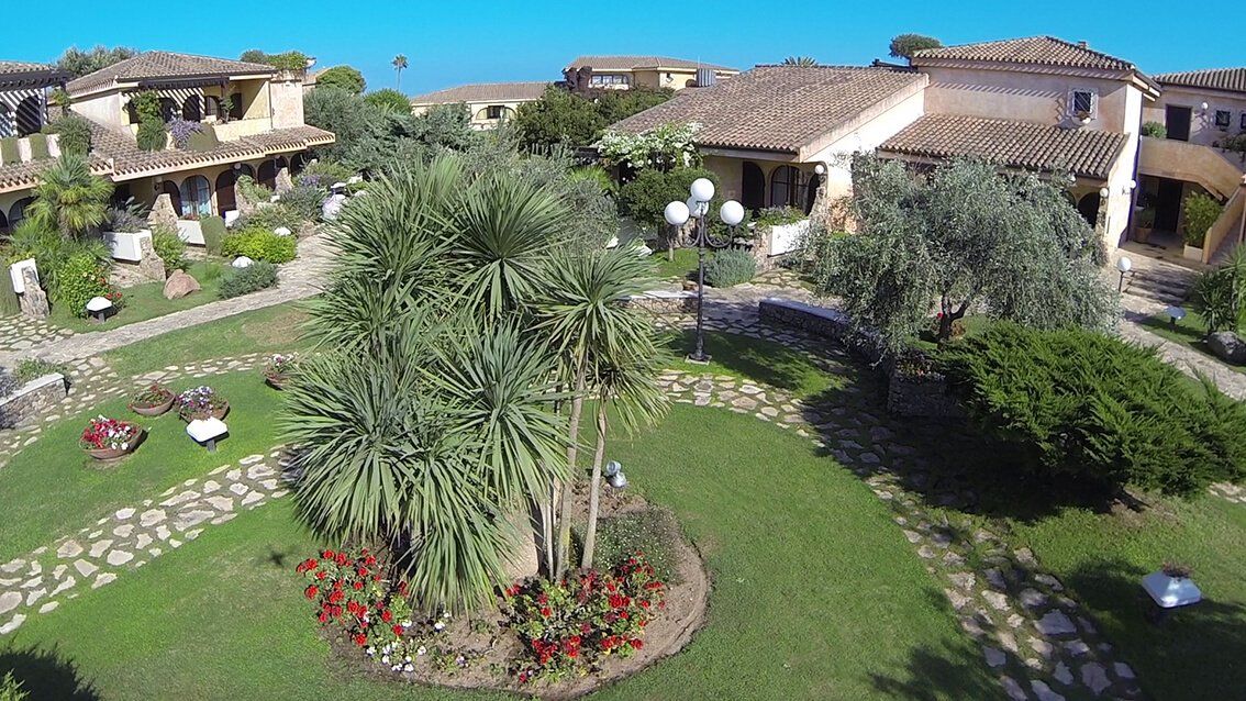spazio verde con prato, sentiero in pietra e alberi ad alto fusto