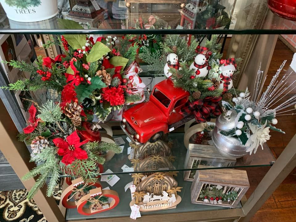 A glass display case filled with christmas decorations and a red truck.