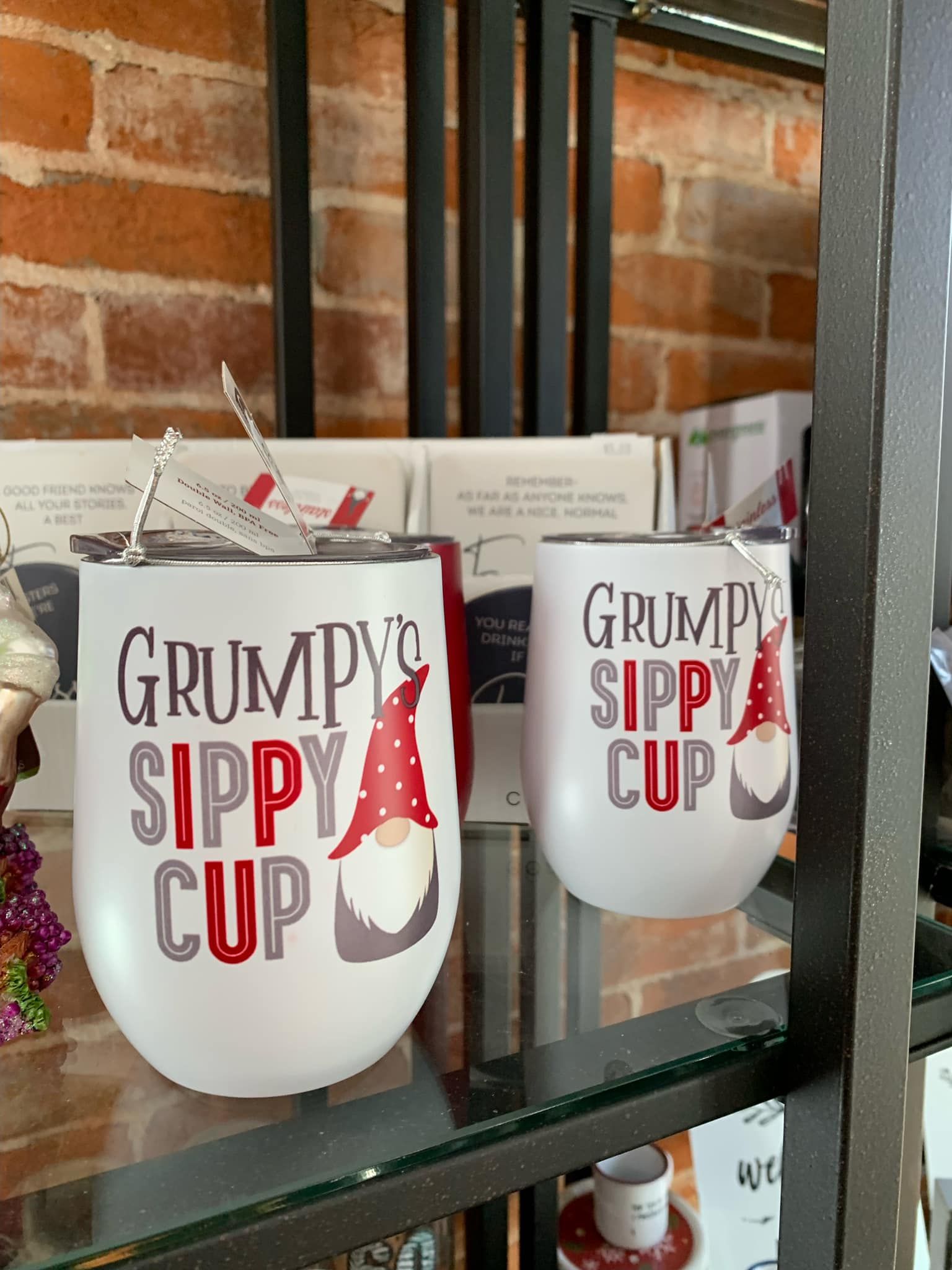 A couple of mugs that say `` grumpy 's sippy cup '' are sitting on a glass shelf.