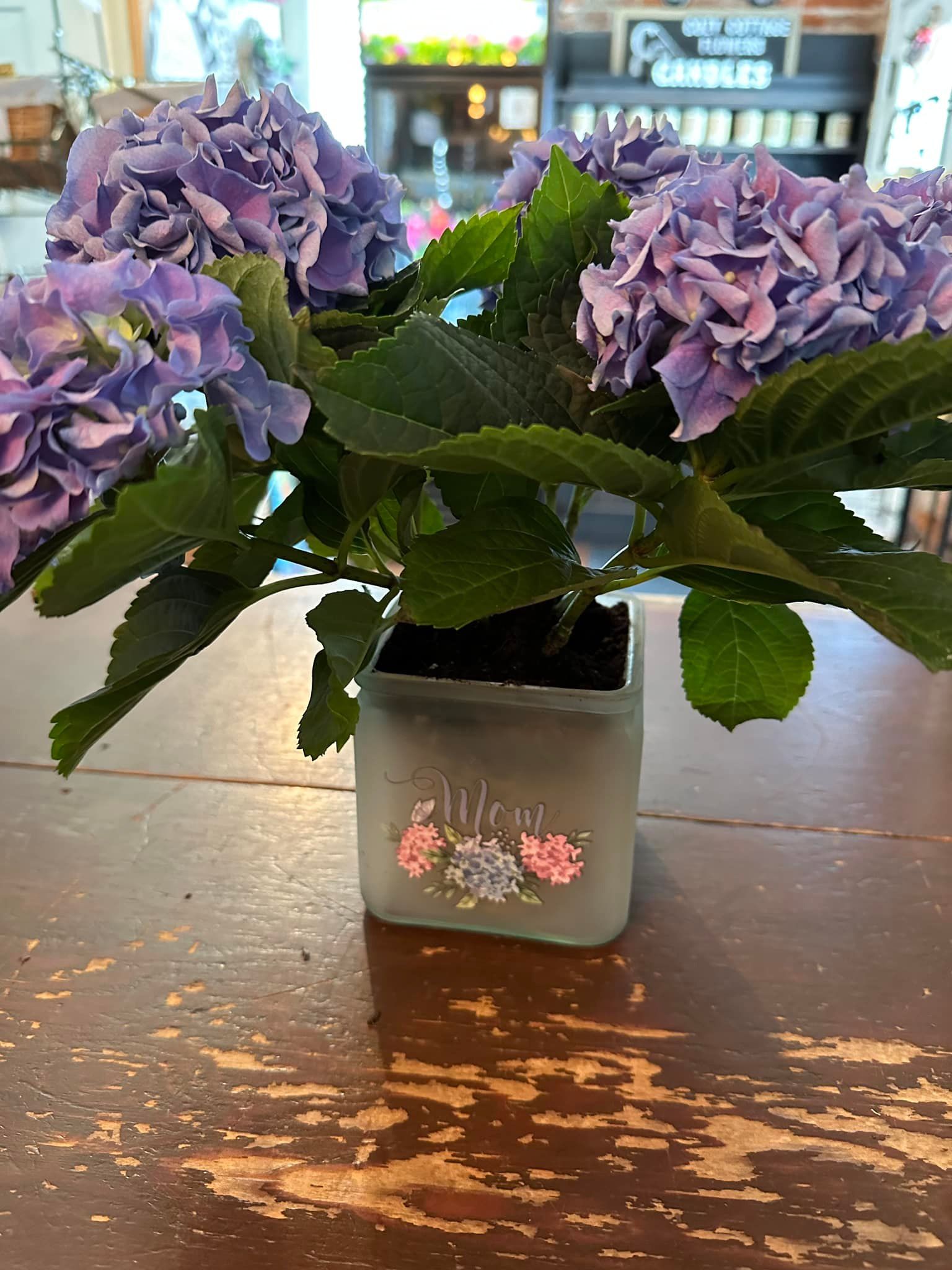 A vase filled with purple flowers is sitting on a wooden table.