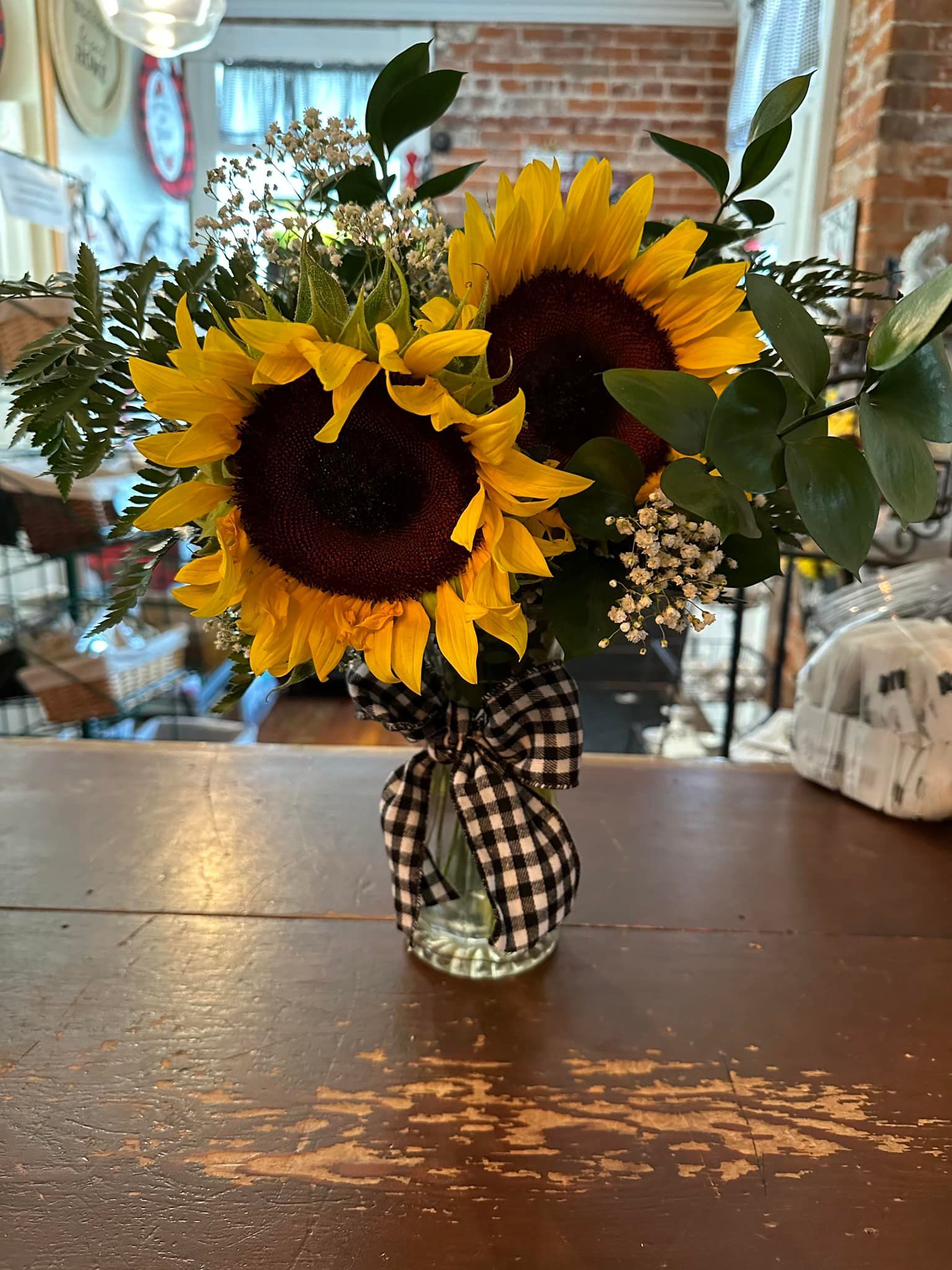 A vase filled with sunflowers is sitting on a wooden table.