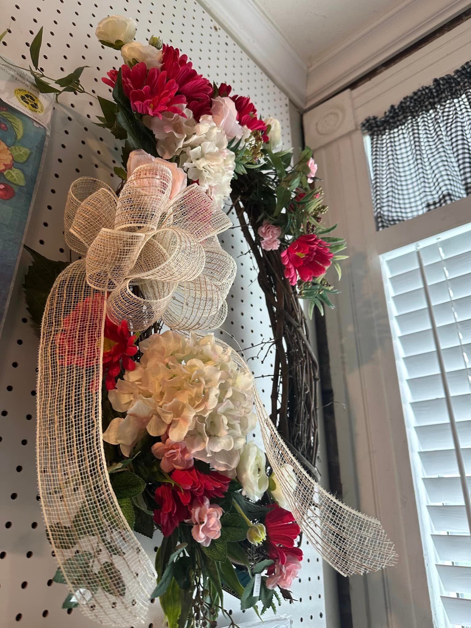 A wreath of flowers is hanging on a wall next to a window.