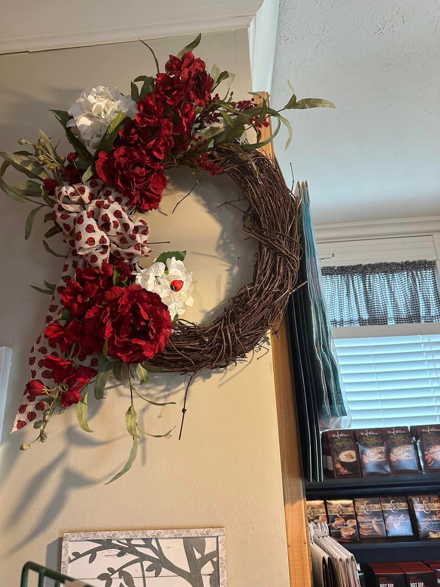 A wreath with red and white flowers is hanging on a wall.