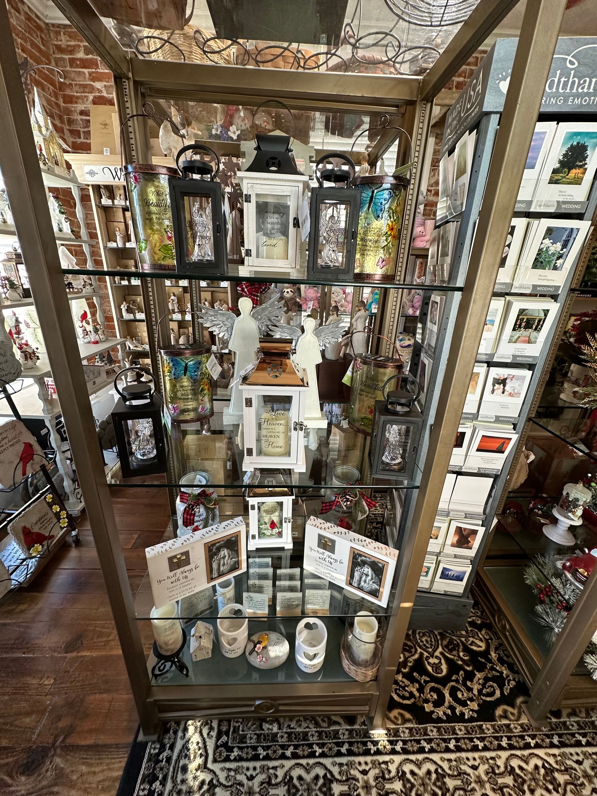 A glass display case filled with candles , cards , and other items.