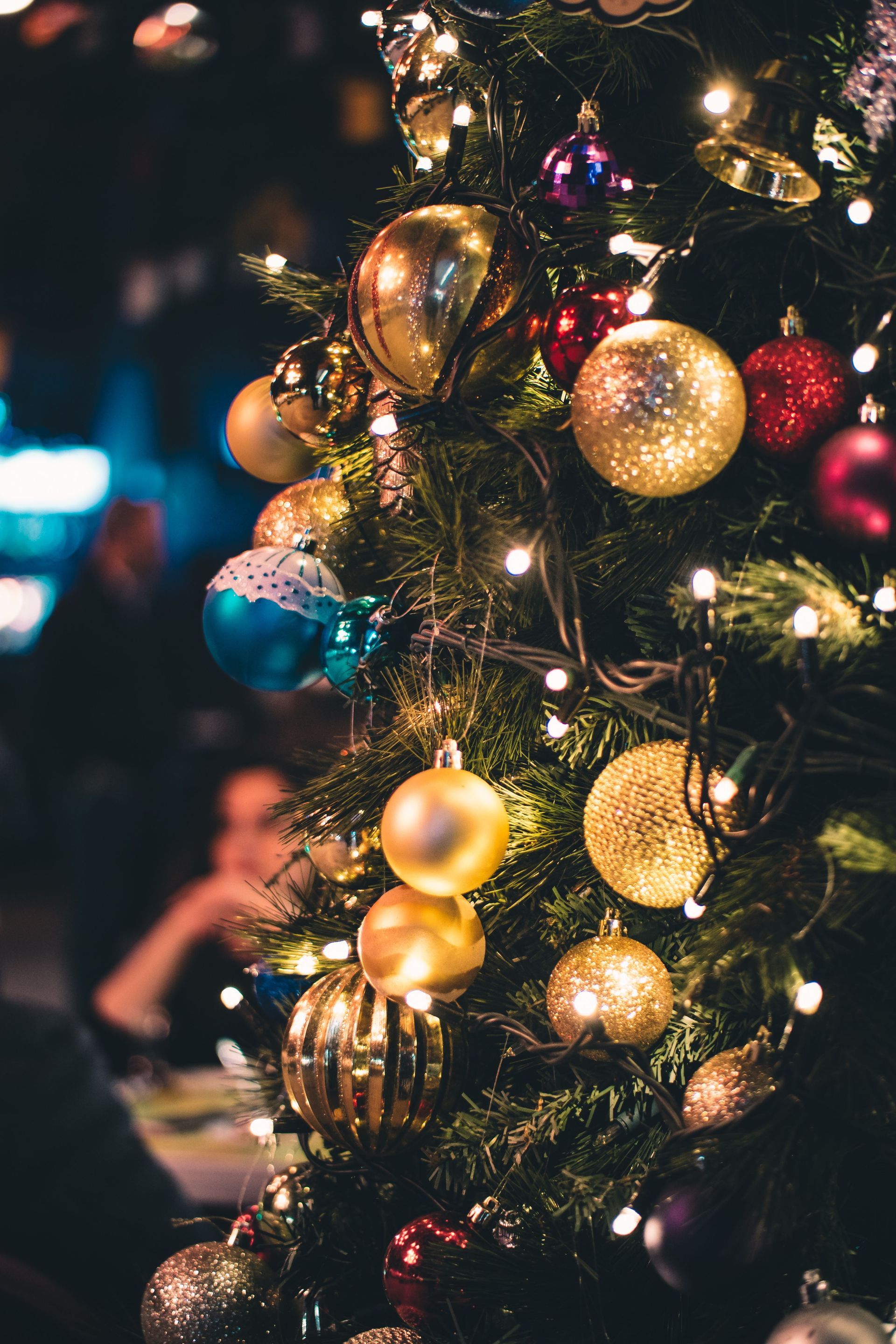 Christmas tree decorated with gold and colorful ornaments and warm fairy lights