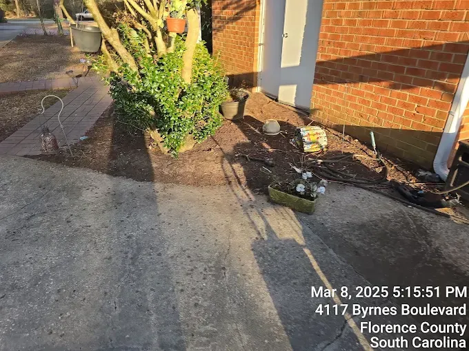 Exterior view of a building with a driveway and small landscaped area. Date/time stamp visible: March 8, 2025, 5:51 PM.