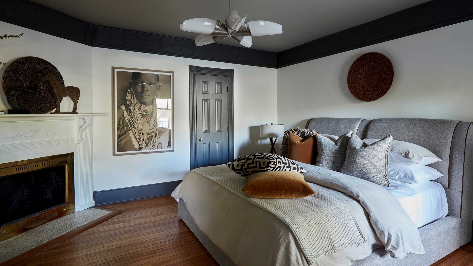 A bedroom with a large bed , fireplace and ceiling fan.