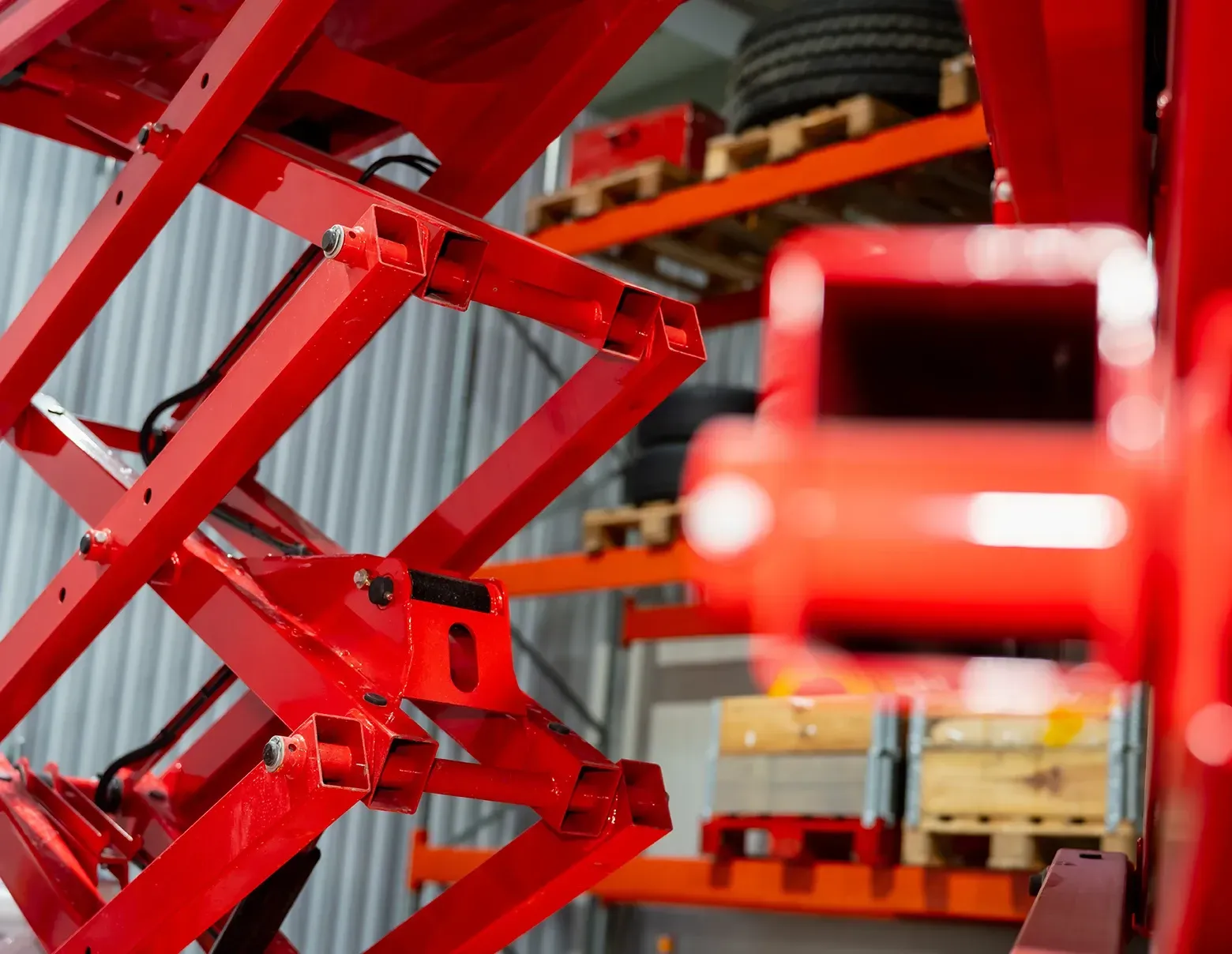 Close em um equipamento hidráulico de elevação na cor vermelha, mostrando sua estrutura mecânica em 