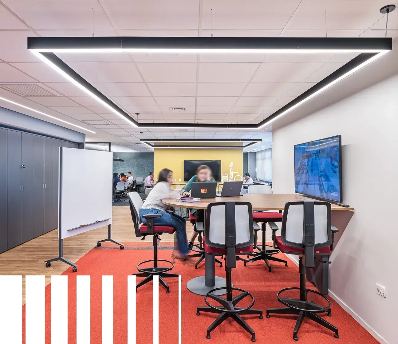 um grupo de pessoas está sentado ao redor de uma mesa com laptops.