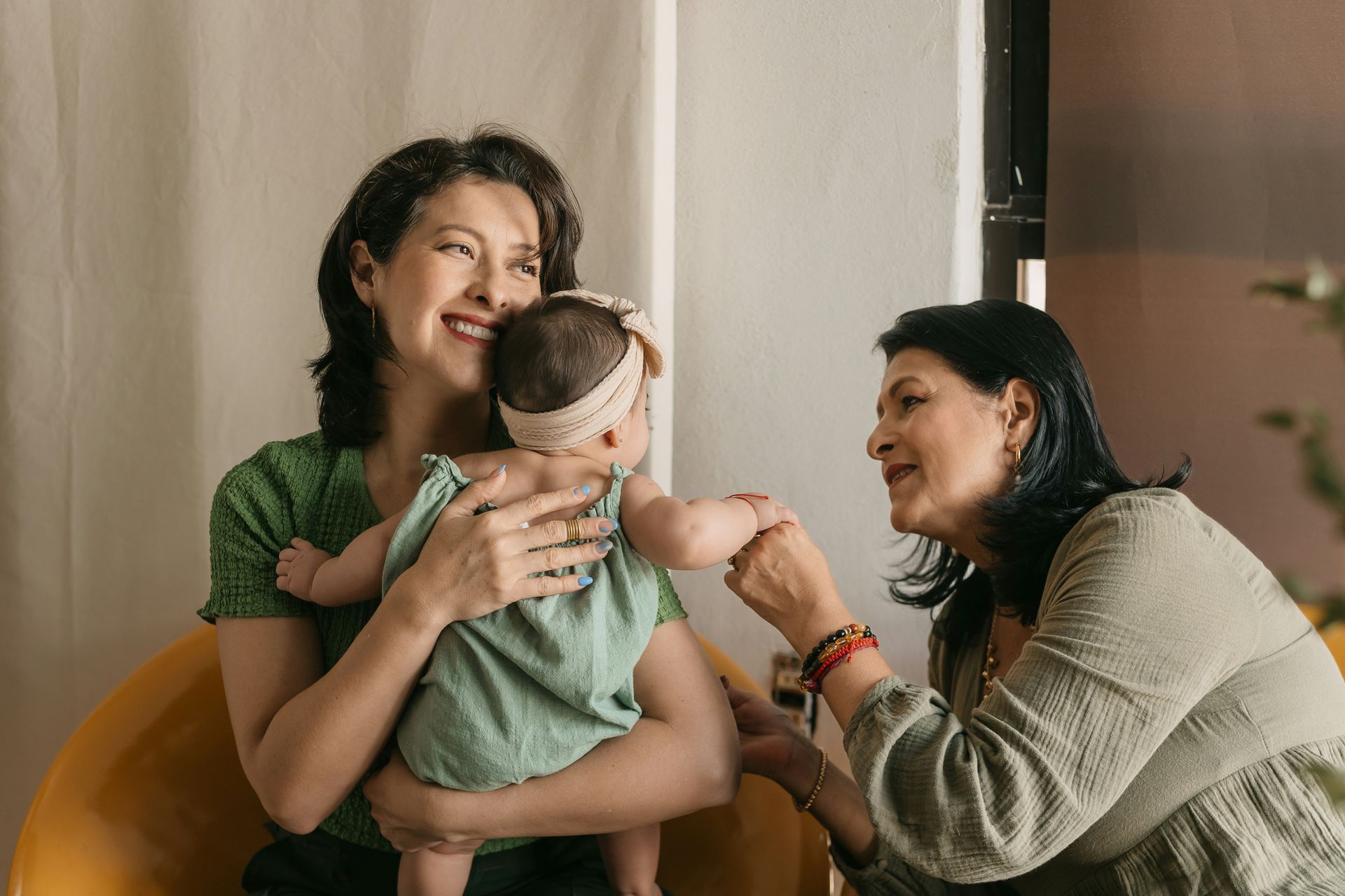A woman is holding a baby while another woman looks on.