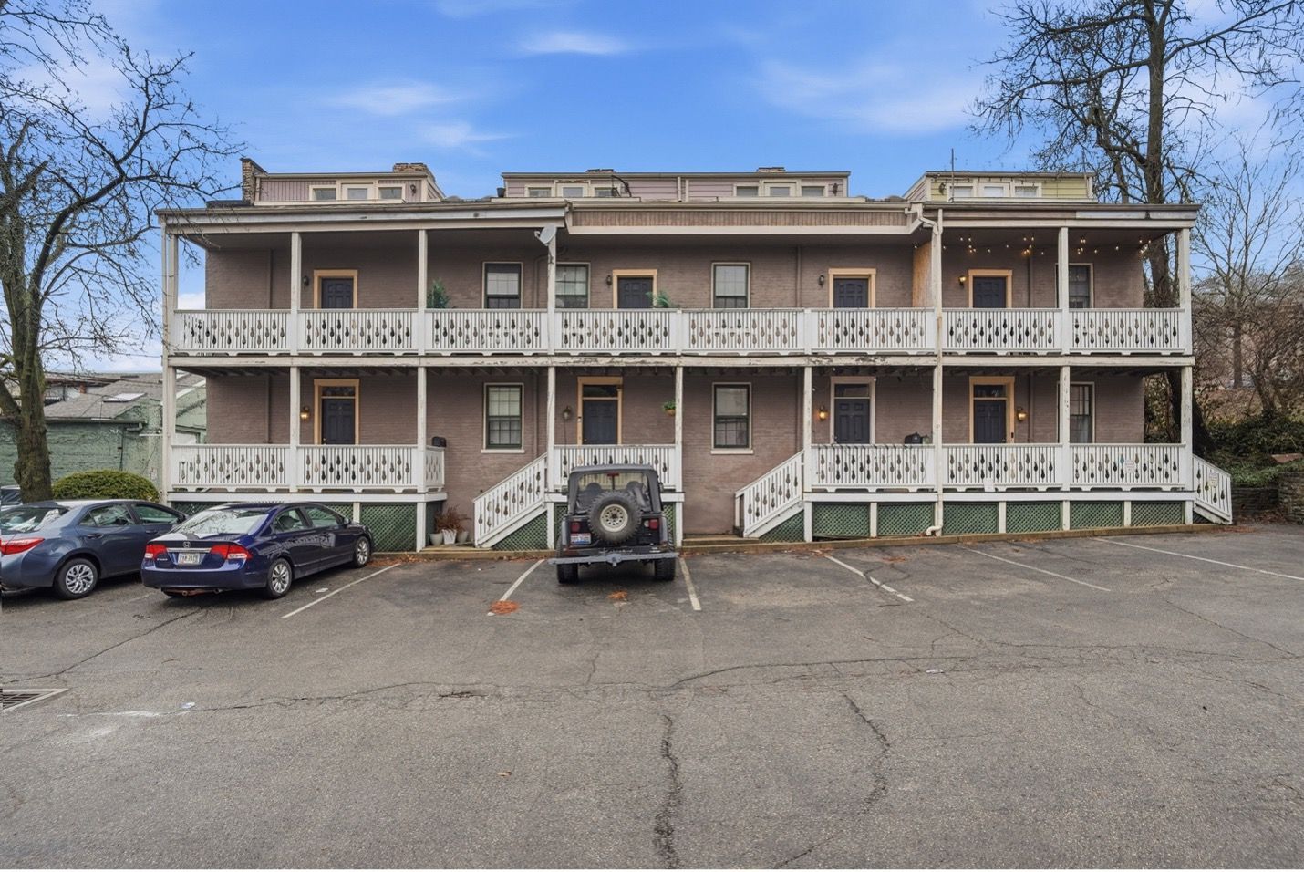 Tall, weathered apartment building with blue and gray facade against a cloudy sky.