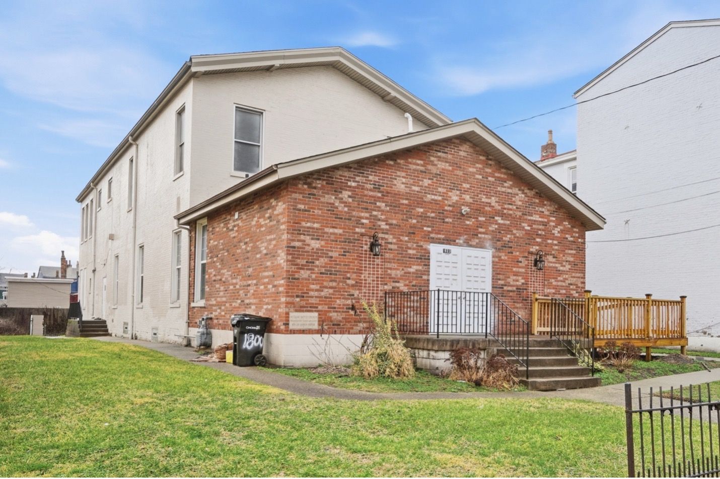 Modern apartment building with brown and white facade, balconies, and blue accents against a bright sky.