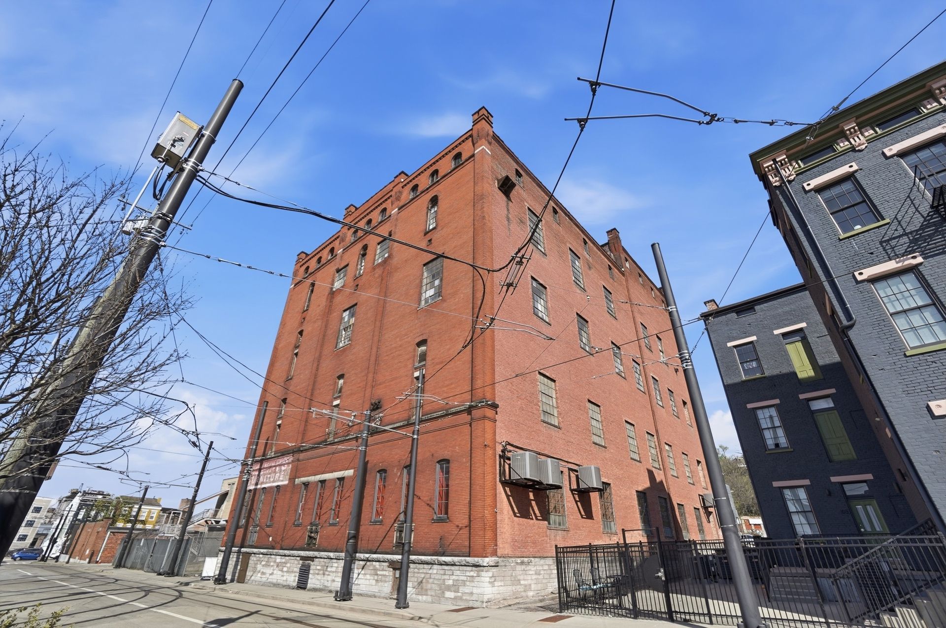 Modern apartment buildings with orange and grey facades and angled rooftops against a blue sky.