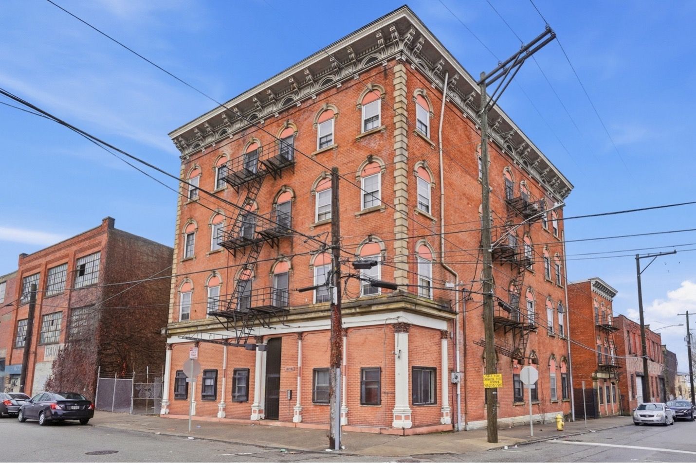 Modern apartment buildings with orange and grey facades and angled rooftops against a blue sky.