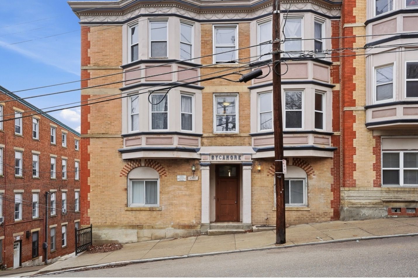 Modern high-rise building with a white facade and red accents against a blue sky.