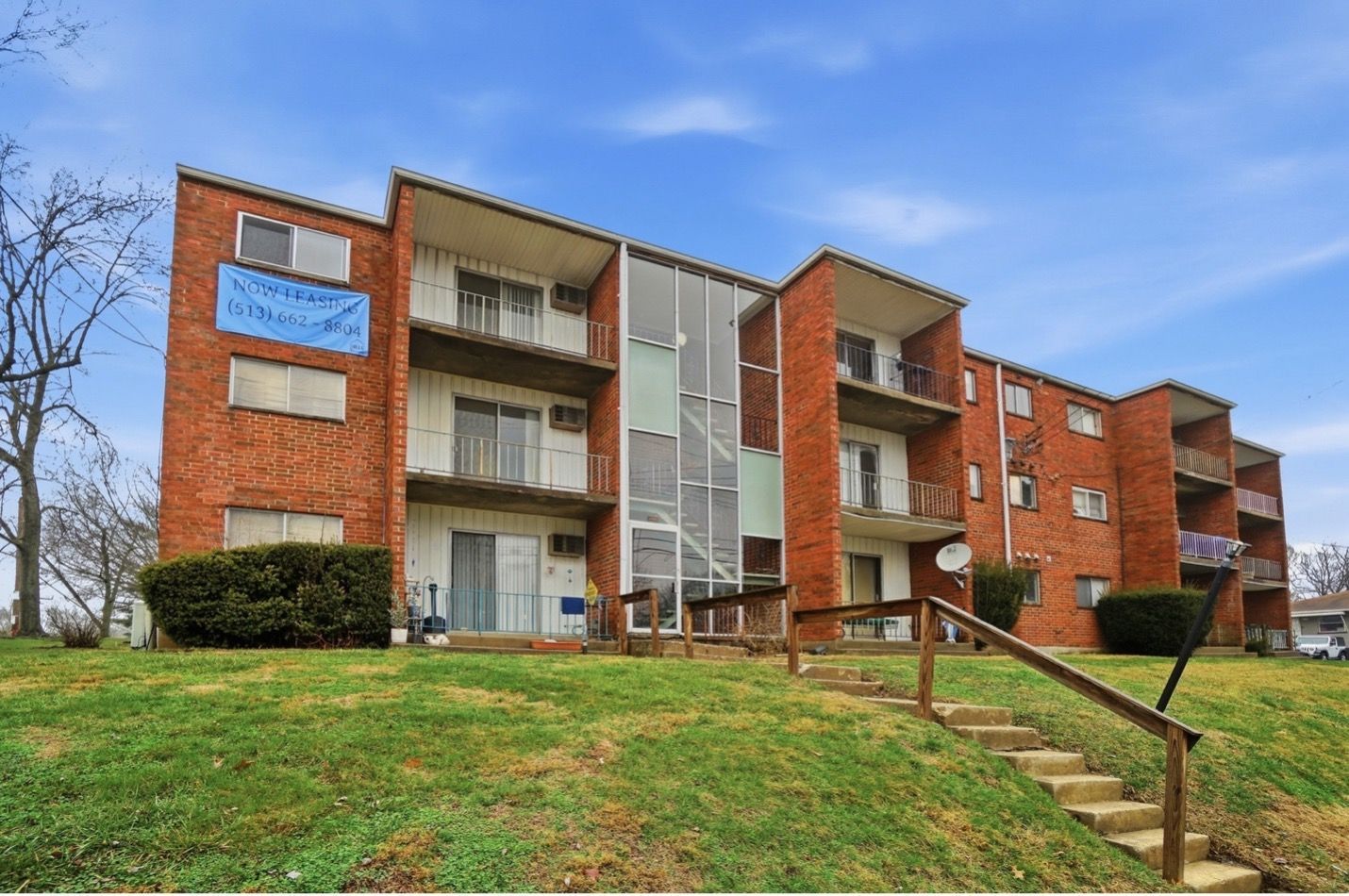 Modern apartment buildings with orange and grey facades and angled rooftops against a blue sky.