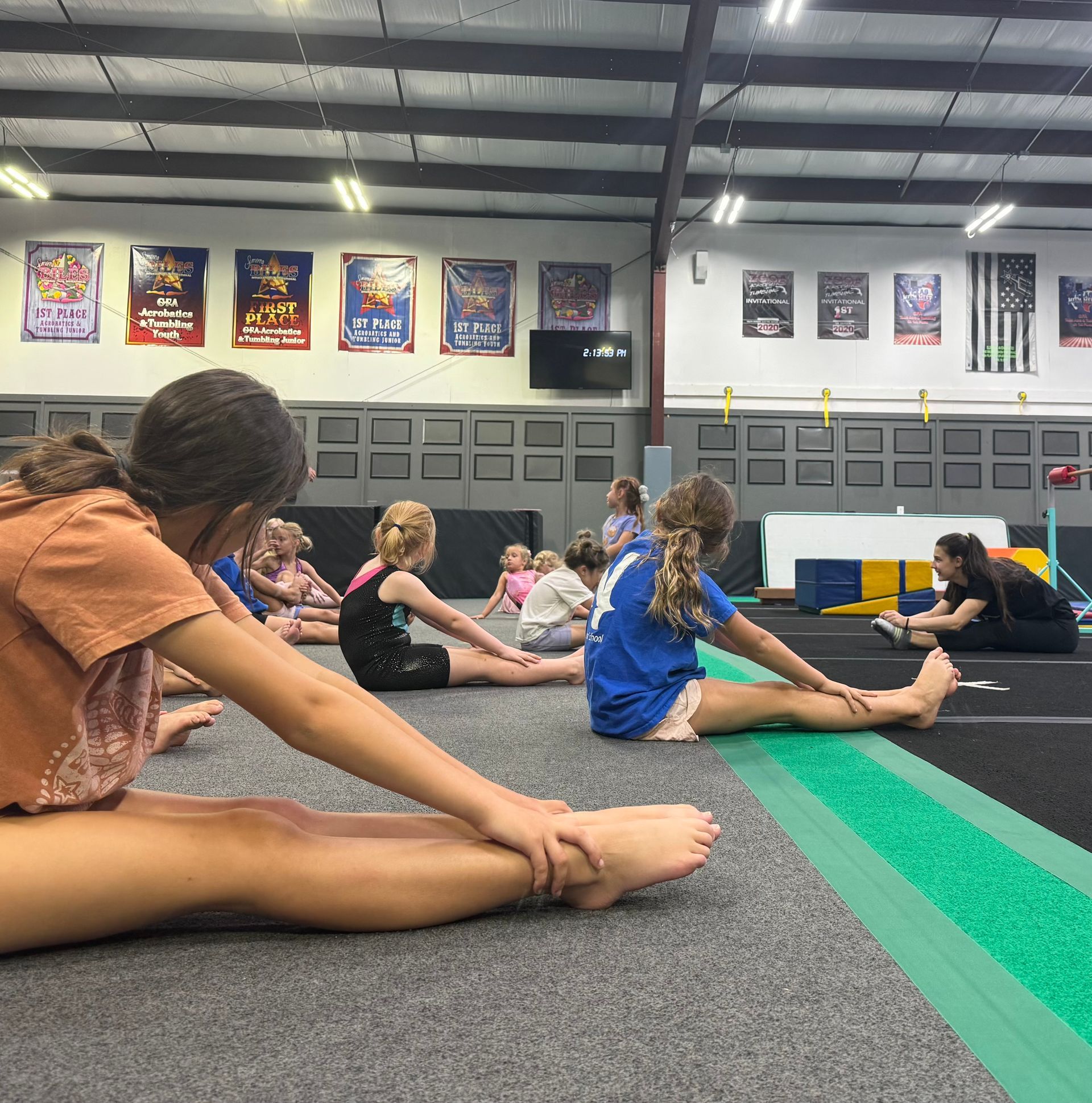 A group of children are sitting on the floor in a gym.