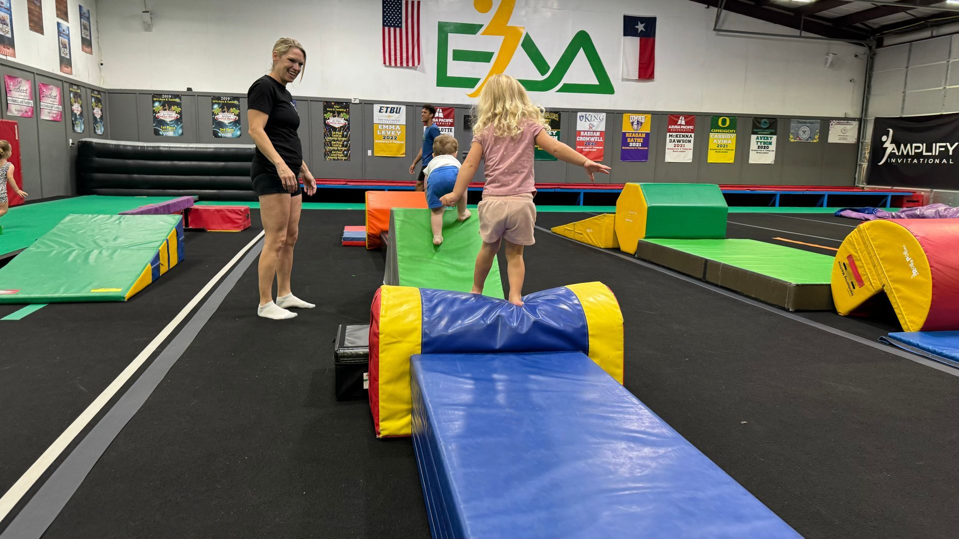 A woman and two children are playing in a gym.