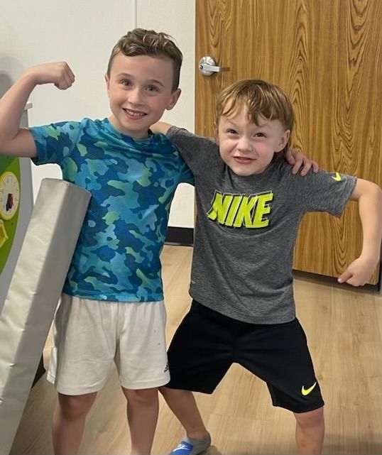 Two boys are posing for a picture and one has a nike shirt on