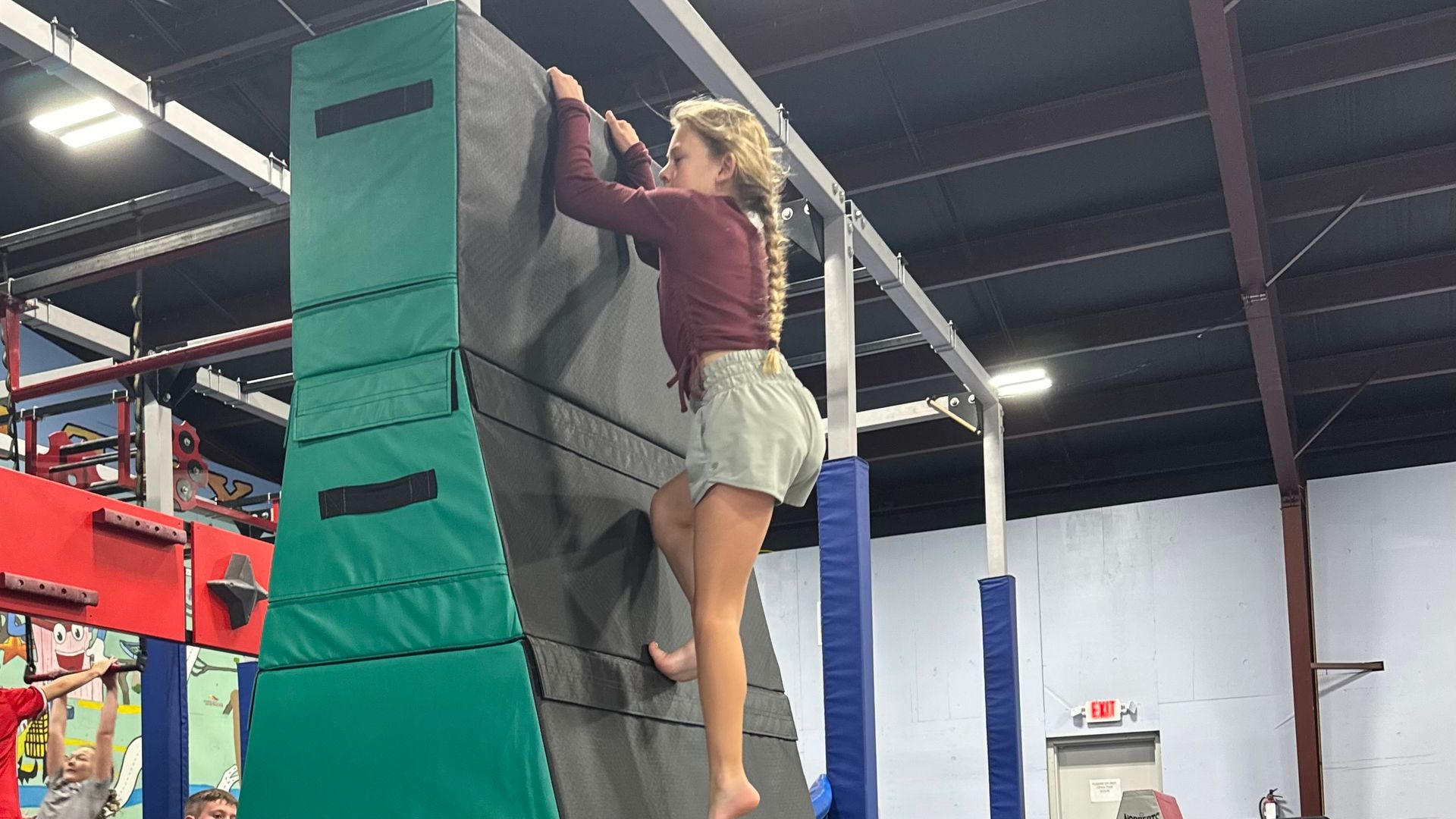 A woman is climbing a climbing wall in a gym.