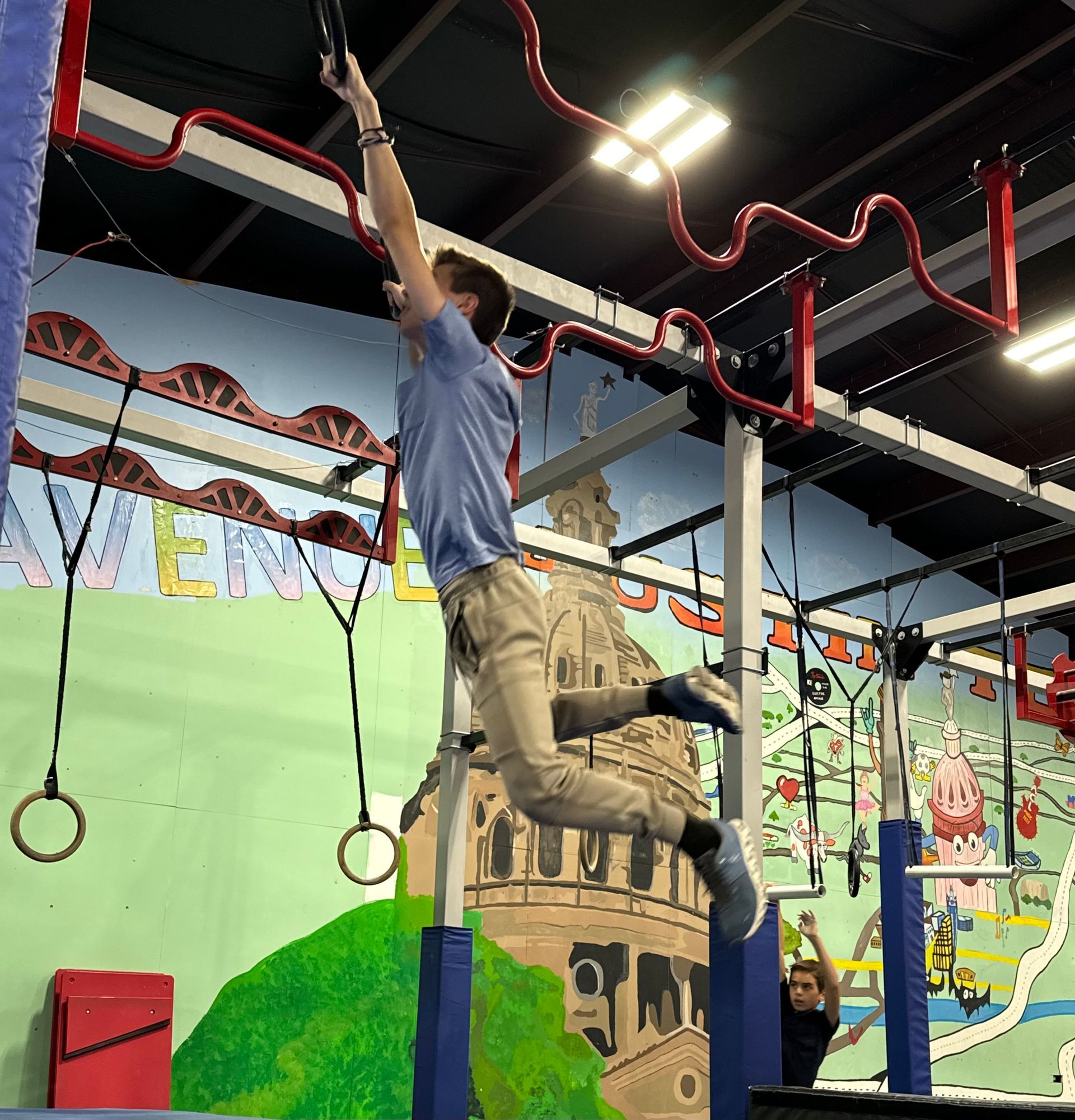 A man is climbing up a rope in a gym