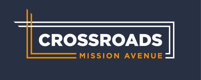 Logo for Crossroads Mission Avenue, white text over a dark blue background. Includes gold and white square accents.