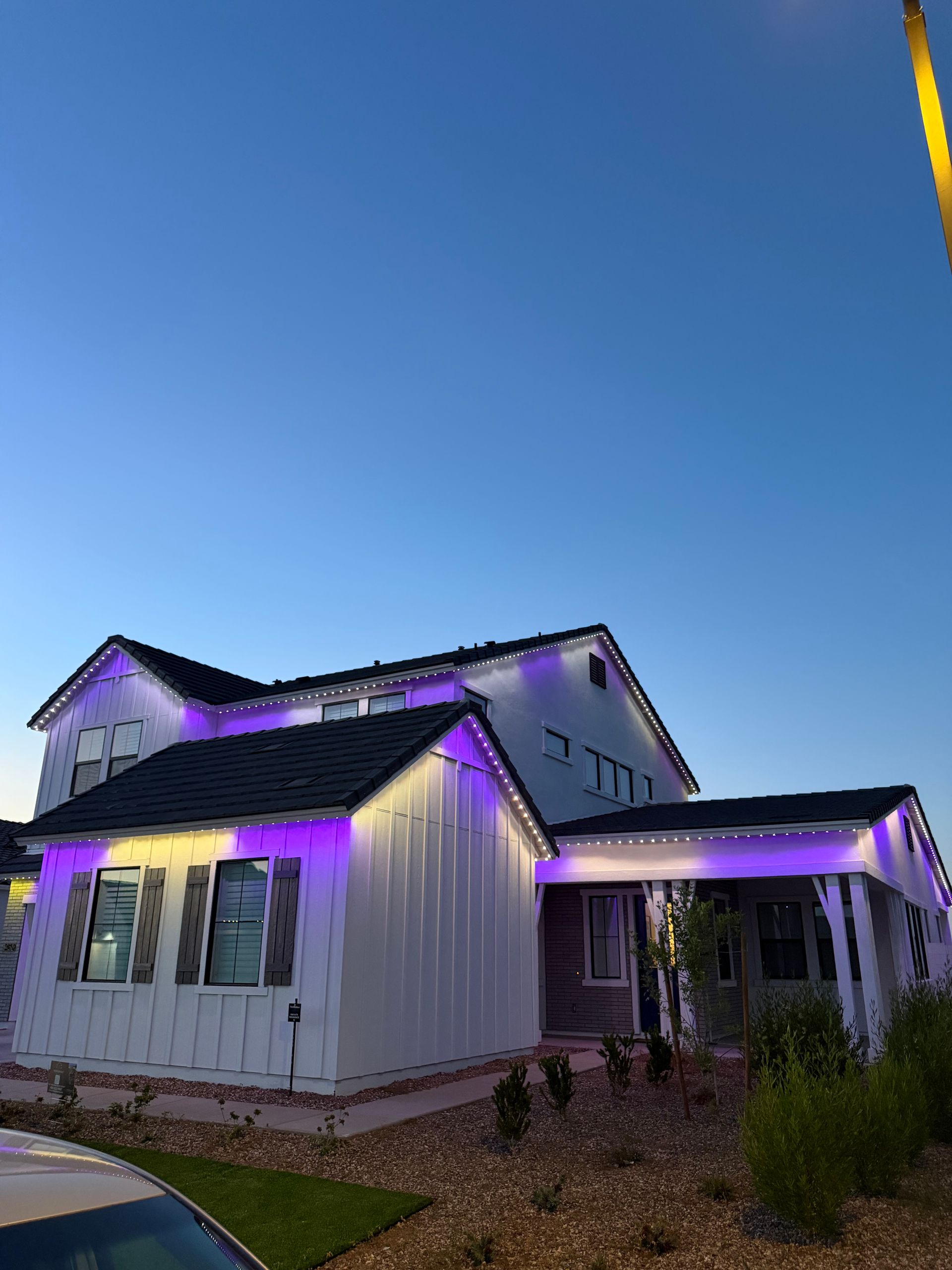 White house with purple accent lights at dusk under a clear blue sky