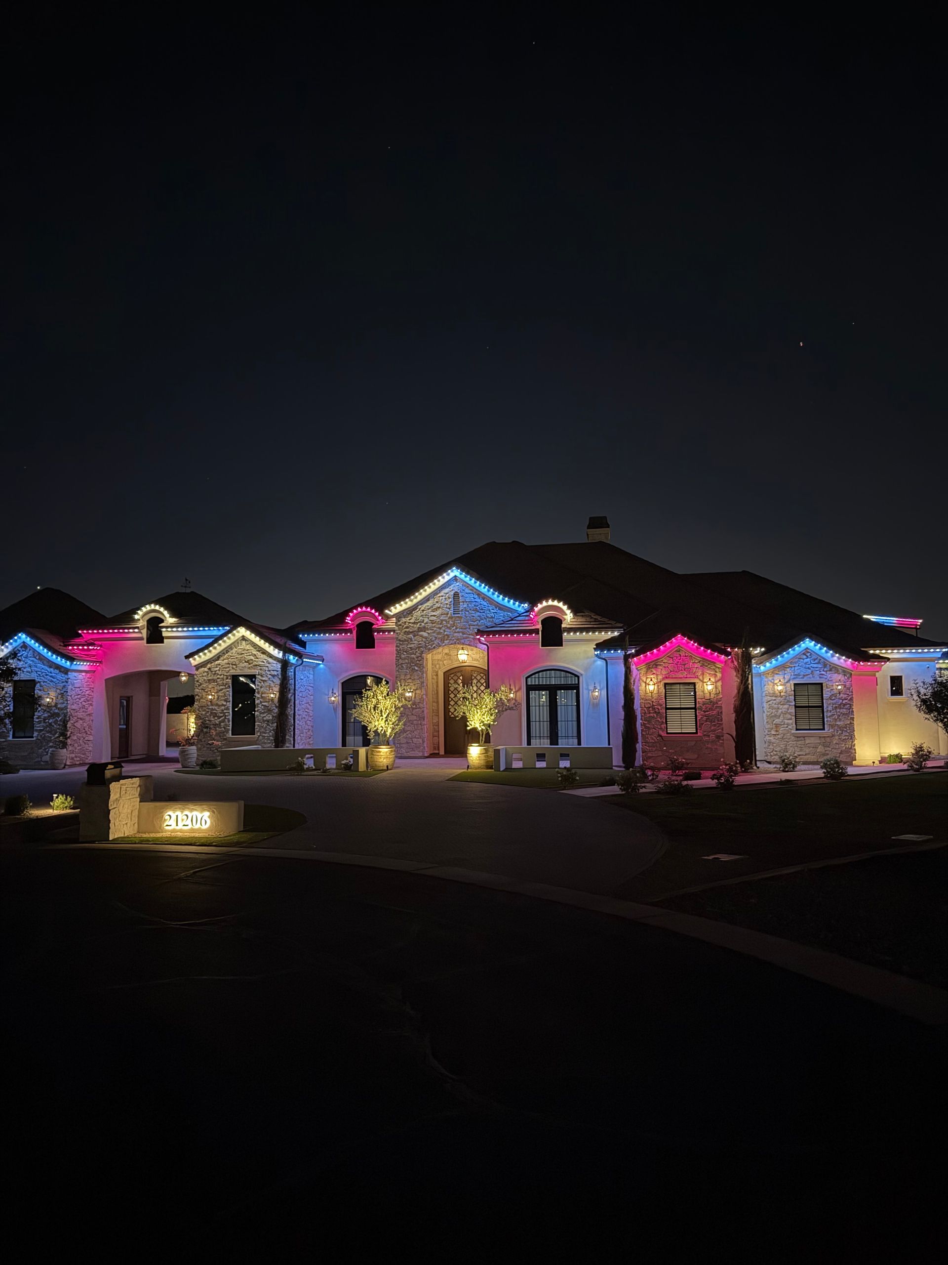 Single-story houses decorated with colorful holiday lights at night
