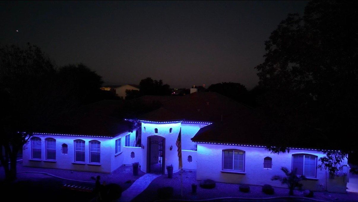House at night, illuminated with blue lights along the roofline and around windows.