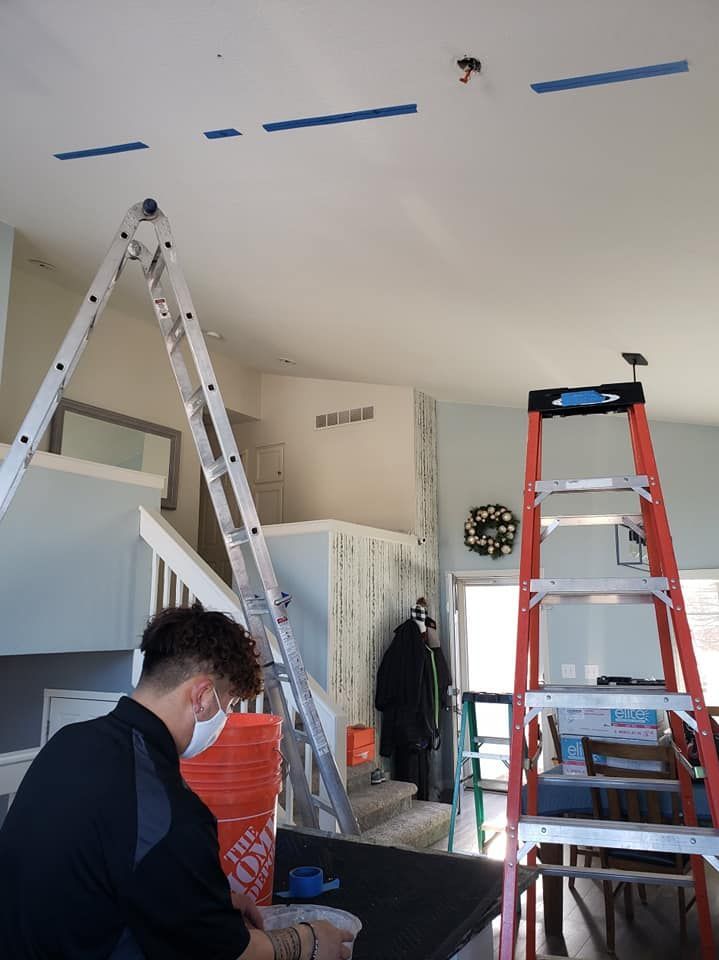 A man is standing on a ladder in a living room.