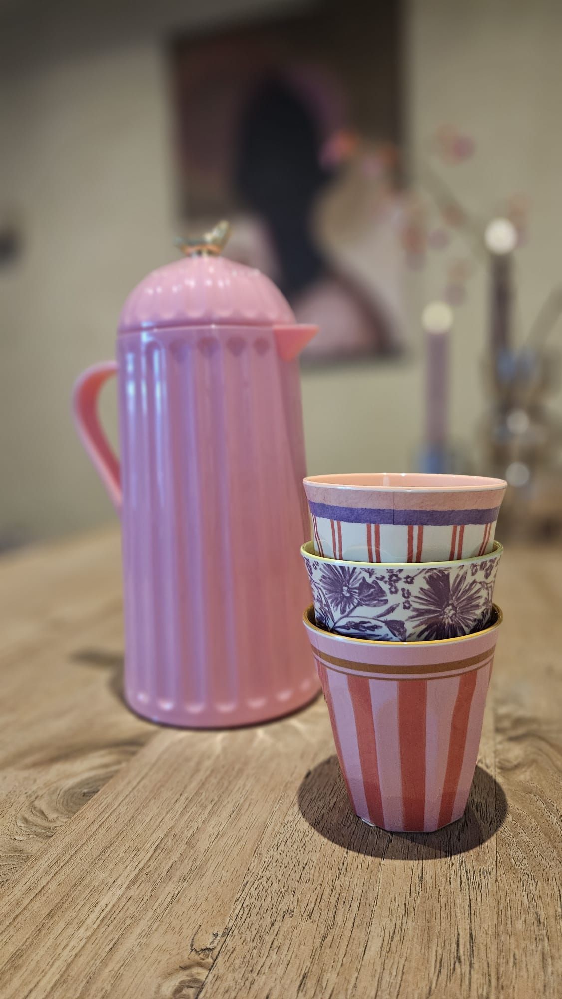 Roze, geïsoleerde karaf op een houten tafel, met een goudkleurig vogeltje op het deksel.
