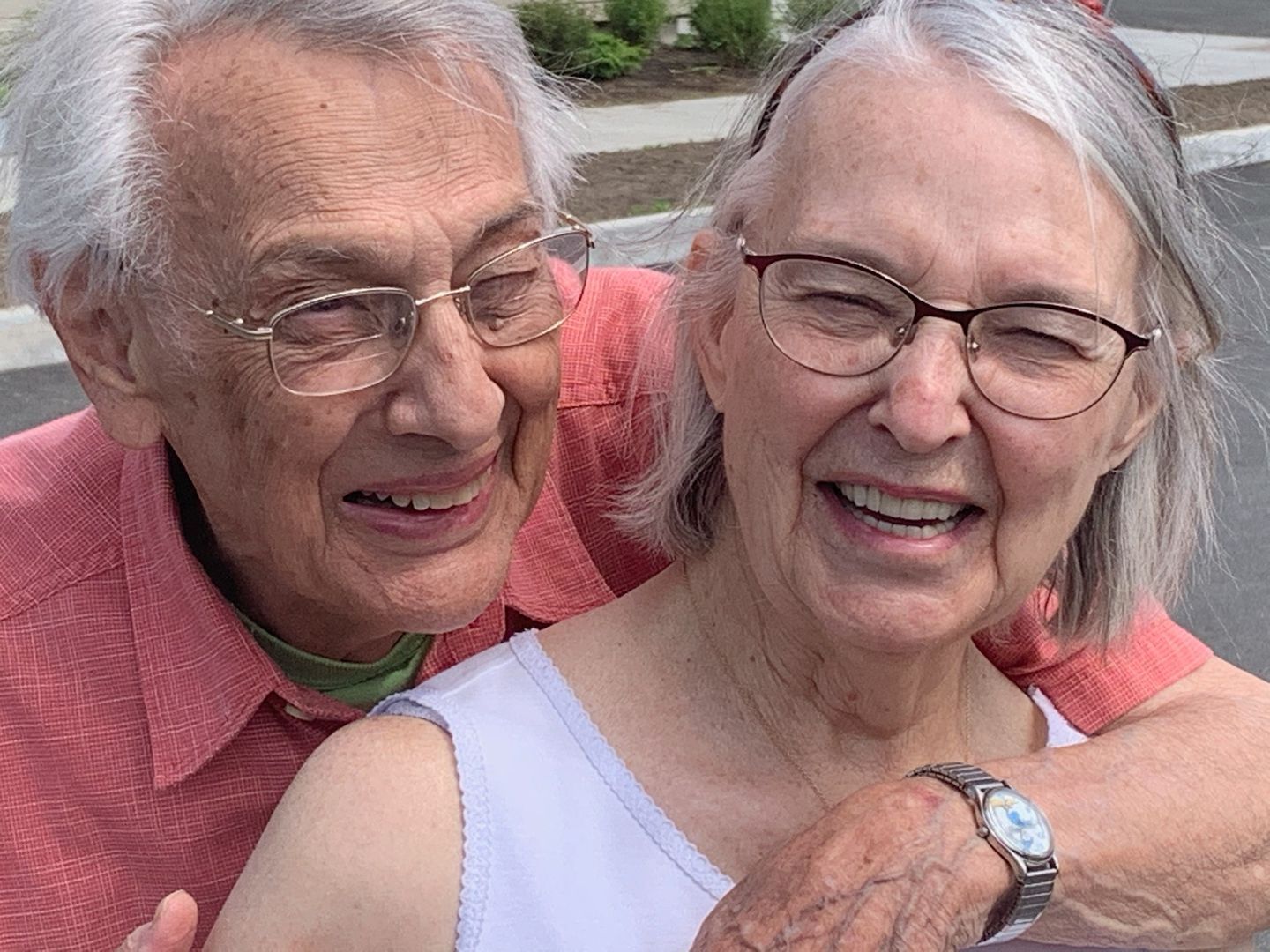 A man and a woman are hugging each other and smiling for the camera