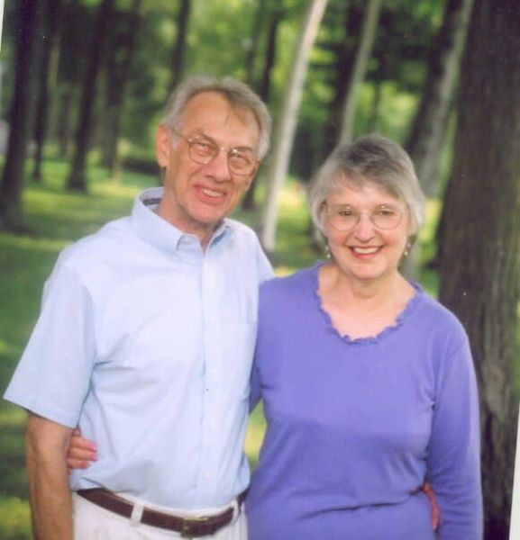A man and woman are posing for a picture in the woods