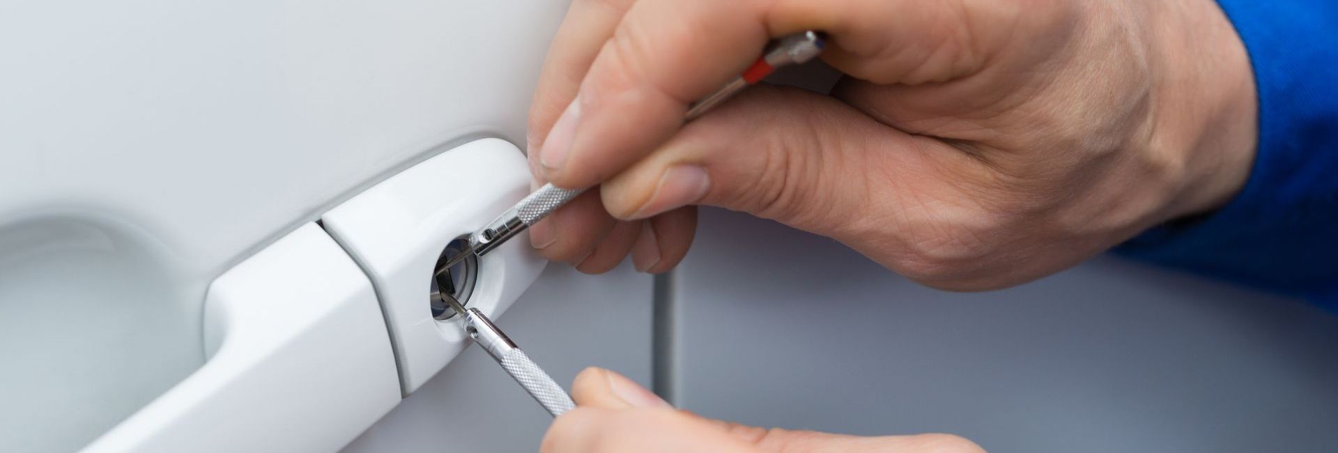A person is using a screwdriver to open a car door.