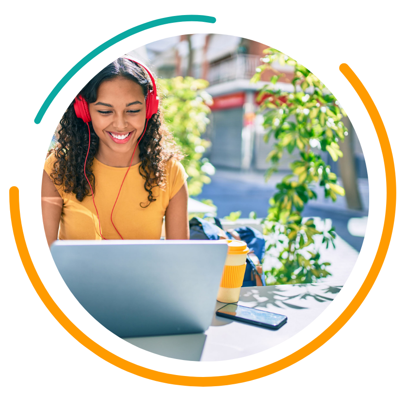 Woman with red headphones smiles at laptop, outdoors.