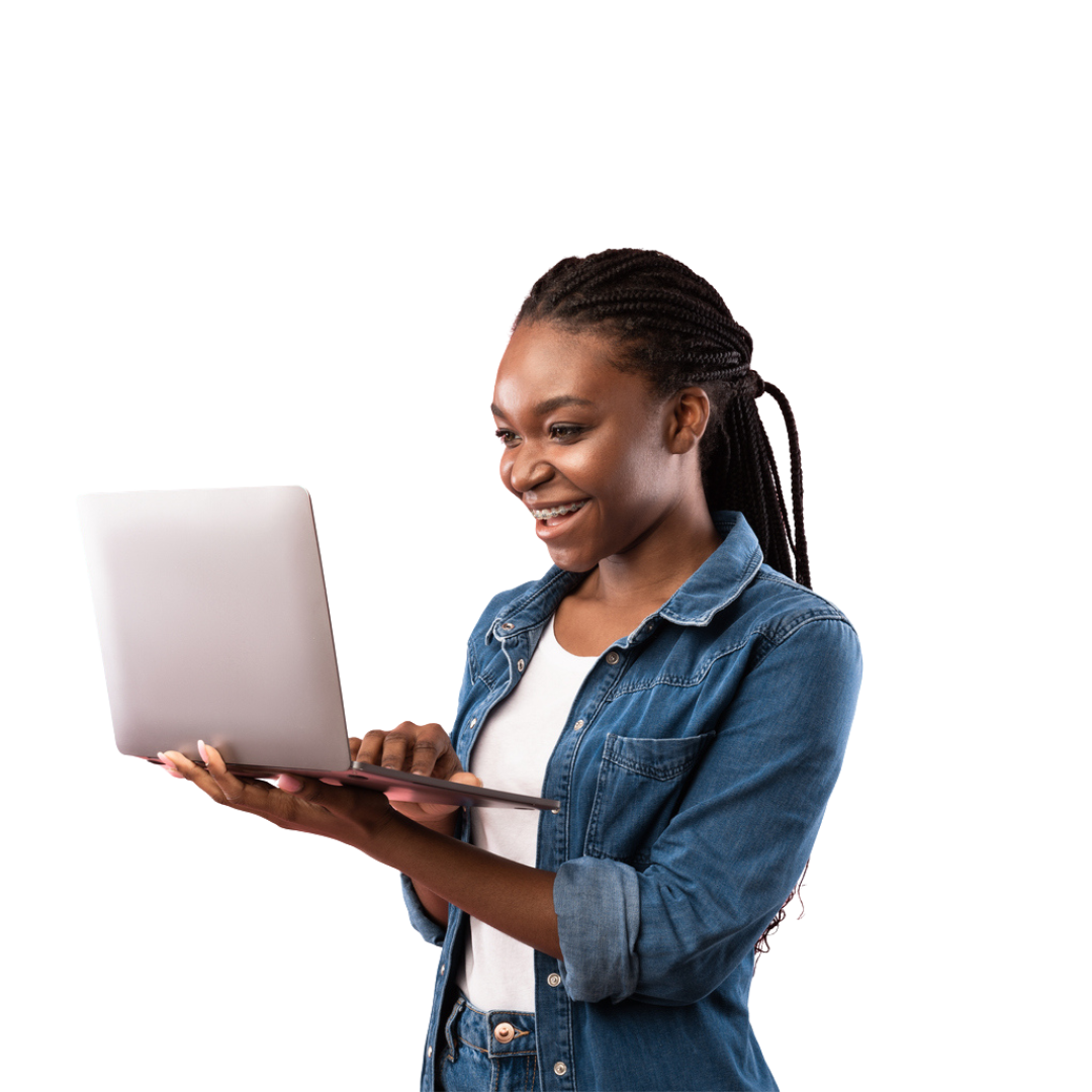 Young Black woman smiles while using a laptop, wearing a denim jacket and white shirt.