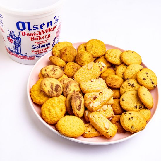 Cookies from Olsen's Danish Village Bakery in a pink plate next to the bakery's container.
