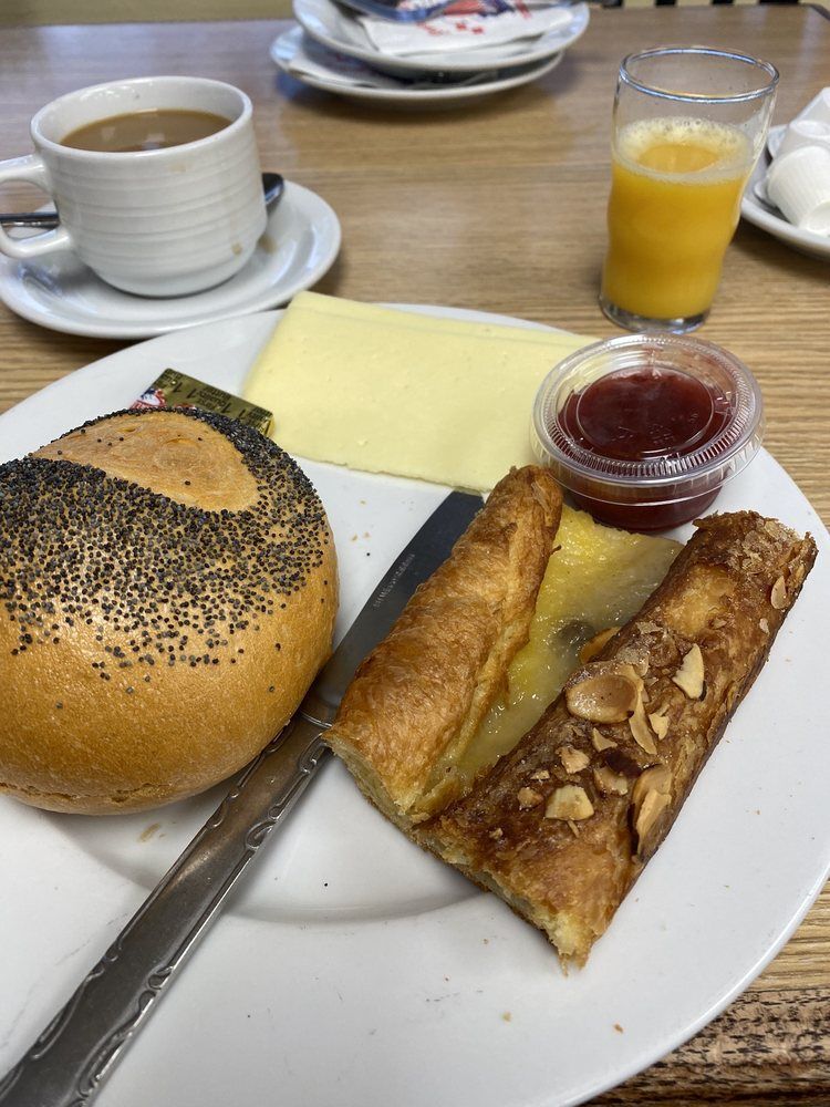 Breakfast plate with bread, cheese, jam, pastry, coffee, and juice.